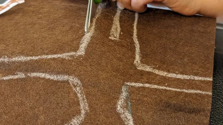 Child is cutting out a doll shape from felt