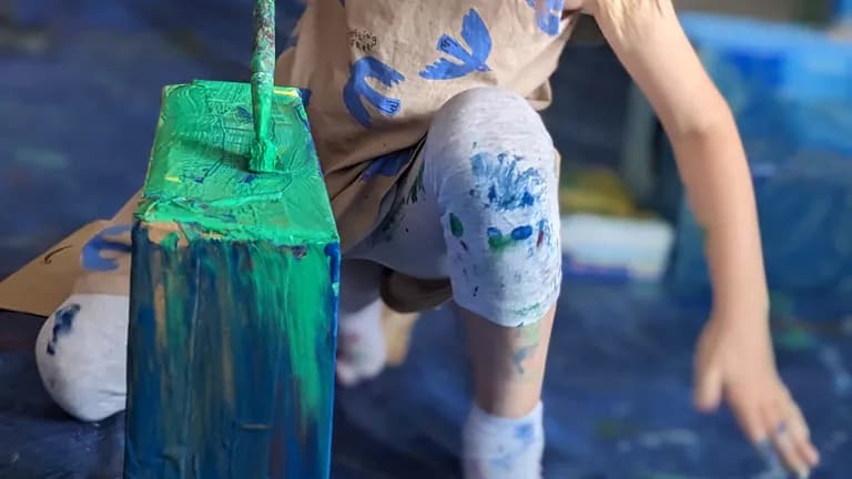 child is painting, covered in paint